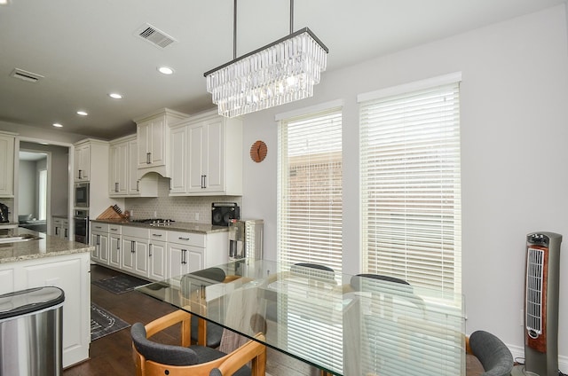 kitchen featuring dark hardwood / wood-style flooring, light stone countertops, hanging light fixtures, and white cabinets