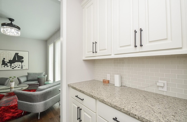 kitchen with white cabinetry, light stone countertops, hardwood / wood-style floors, and backsplash