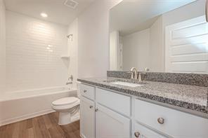 full bathroom with vanity, hardwood / wood-style flooring, shower / bathtub combination, and toilet