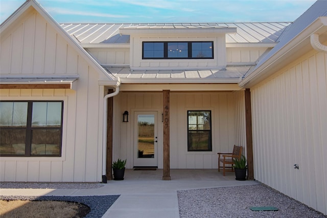 doorway to property with a porch, board and batten siding, a standing seam roof, and metal roof