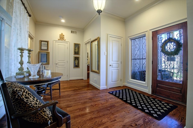 entryway with ornamental molding and dark hardwood / wood-style floors