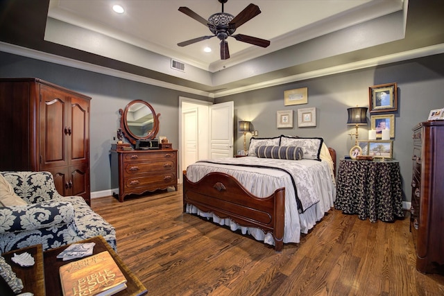 bedroom with crown molding, dark hardwood / wood-style flooring, and a raised ceiling