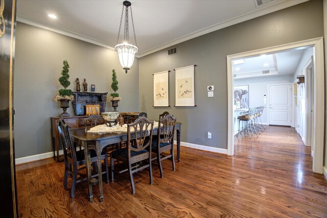 dining room featuring a fireplace, dark wood-type flooring, and ornamental molding