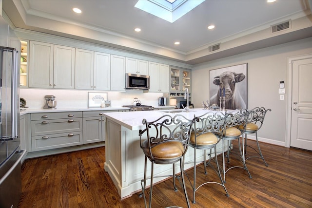 kitchen featuring a center island with sink, a breakfast bar, and appliances with stainless steel finishes