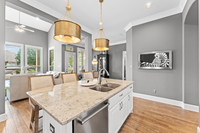 kitchen with a sink, light wood-style floors, open floor plan, stainless steel dishwasher, and ornamental molding