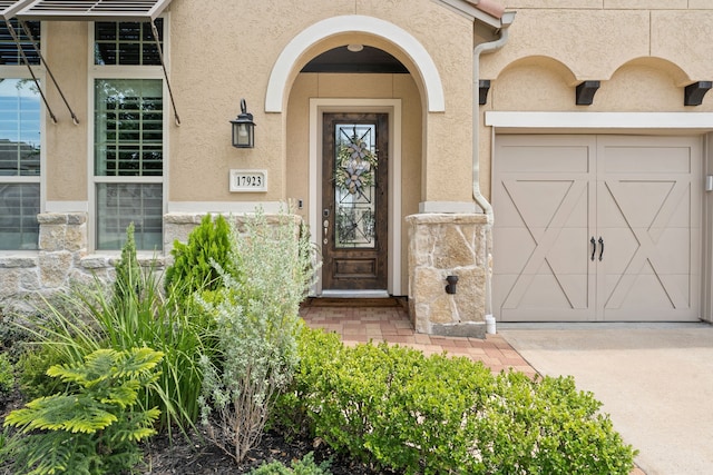 view of exterior entry with driveway, stucco siding, and a garage