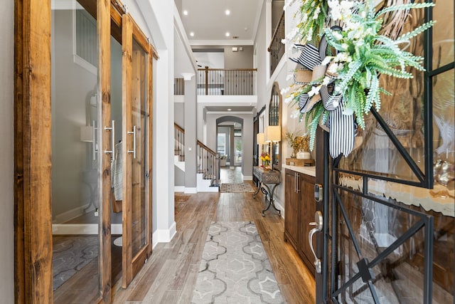 entryway with hardwood / wood-style floors, ornamental molding, and a high ceiling