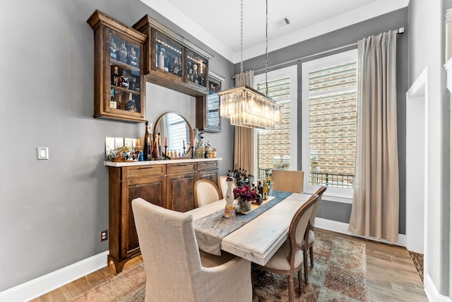 dining area with light wood-style floors, visible vents, baseboards, and an inviting chandelier