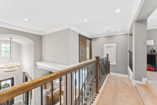 hallway featuring carpet, a chandelier, baseboards, and ornamental molding