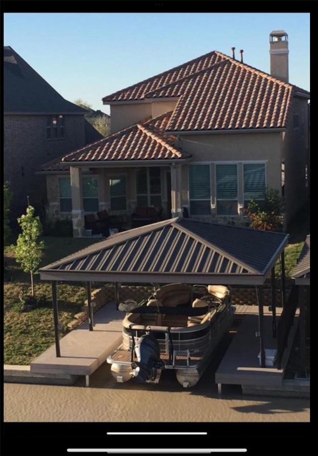 back of house with a tiled roof and stucco siding