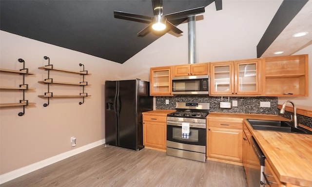 kitchen with sink, appliances with stainless steel finishes, butcher block counters, backsplash, and light hardwood / wood-style floors