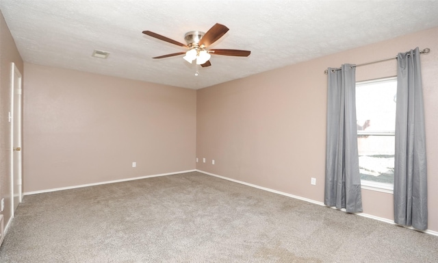 carpeted spare room with ceiling fan, a textured ceiling, and a wealth of natural light