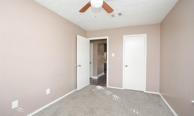 unfurnished bedroom featuring ceiling fan, carpet flooring, and a textured ceiling