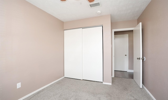 unfurnished bedroom featuring light colored carpet, a closet, and ceiling fan