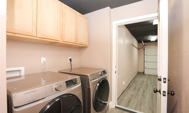 laundry room featuring light hardwood / wood-style flooring, washing machine and dryer, and cabinets