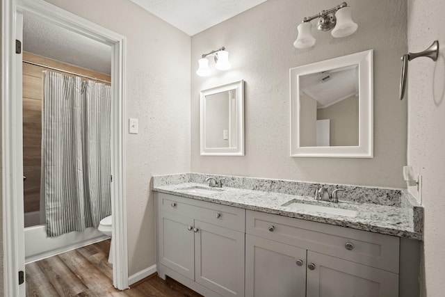 full bathroom with vanity, wood-type flooring, a textured ceiling, toilet, and shower / bath combo with shower curtain