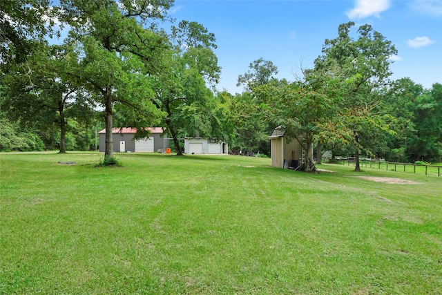 view of yard featuring a storage unit, an outbuilding, and fence