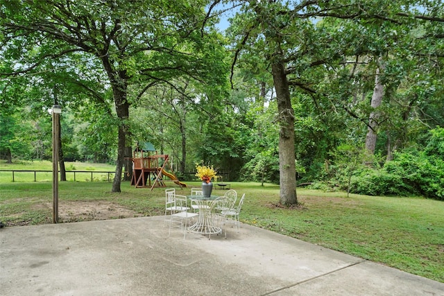 view of patio featuring a playground and fence