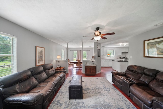 living room featuring visible vents, a textured ceiling, and ceiling fan