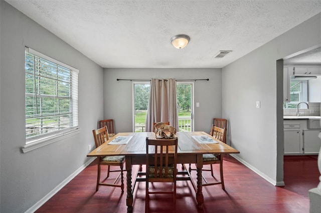 dining area featuring a wealth of natural light, visible vents, and dark wood-type flooring