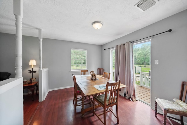 dining space with visible vents, a textured ceiling, baseboards, and wood finished floors