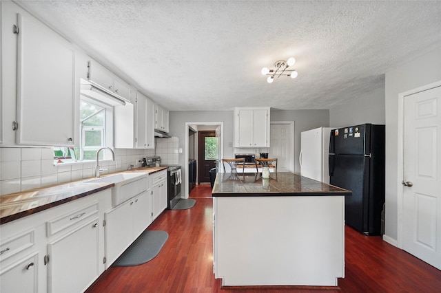 kitchen featuring stainless steel range with electric stovetop, dark wood-style flooring, a center island, and freestanding refrigerator