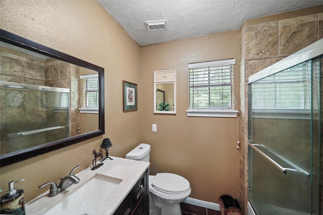 full bath featuring a wealth of natural light, visible vents, toilet, and a tile shower