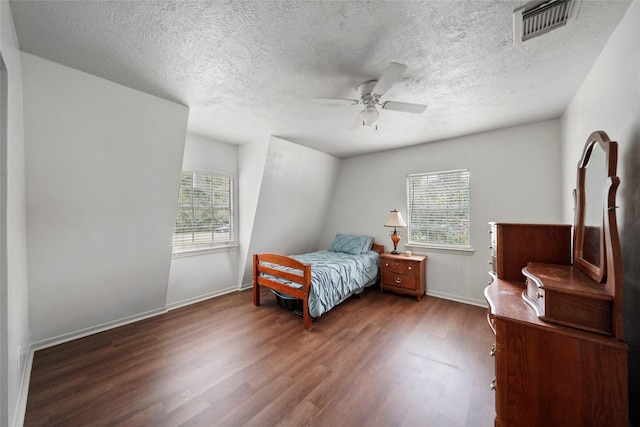 bedroom featuring visible vents, a ceiling fan, a textured ceiling, baseboards, and dark wood-style flooring