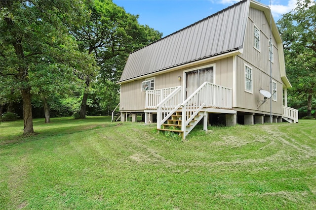 rear view of house featuring a gambrel roof, metal roof, and a yard