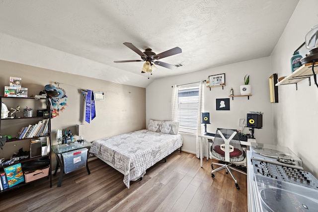 bedroom with lofted ceiling, ceiling fan, hardwood / wood-style flooring, and a textured ceiling