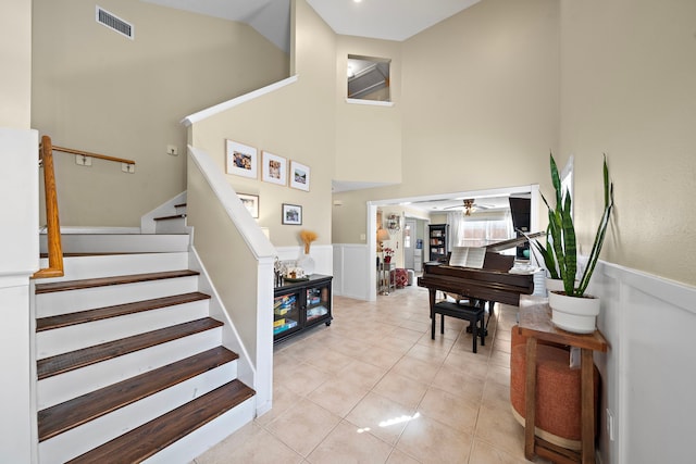 stairs featuring a high ceiling, tile patterned floors, and ceiling fan