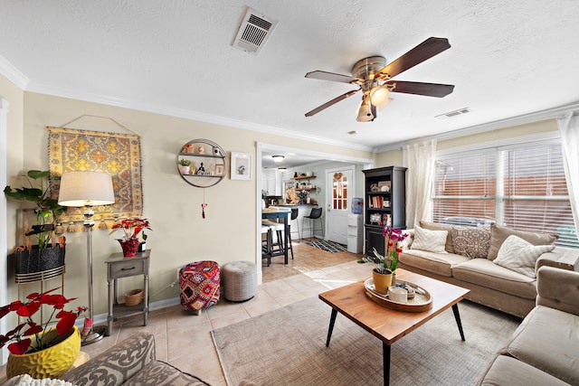 tiled living room featuring ceiling fan, ornamental molding, and a textured ceiling