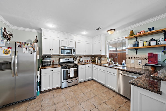 kitchen featuring sink, crown molding, appliances with stainless steel finishes, dark stone countertops, and white cabinets