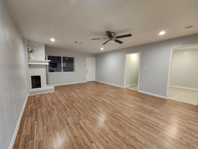 unfurnished living room featuring a brick fireplace, light hardwood / wood-style flooring, and ceiling fan