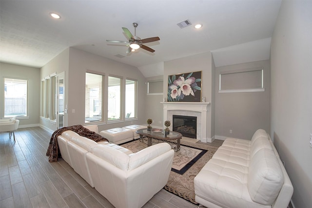 living room featuring a tiled fireplace, ceiling fan, and light wood-type flooring