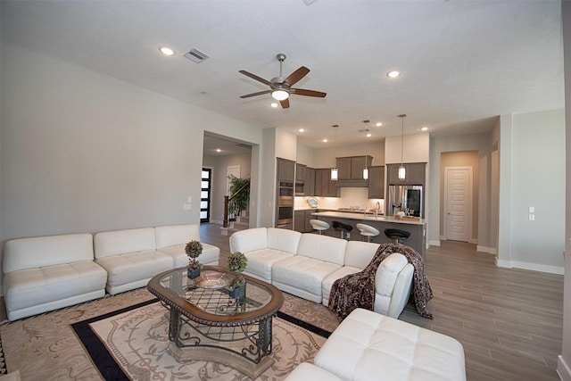 living room with ceiling fan and light hardwood / wood-style flooring