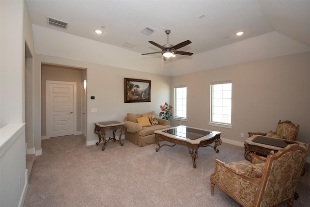 living room with light colored carpet, a raised ceiling, and ceiling fan