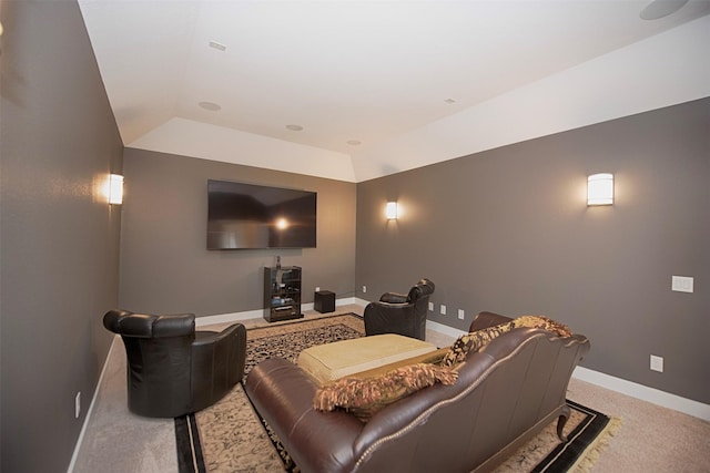 home theater room with a tray ceiling, vaulted ceiling, and light colored carpet