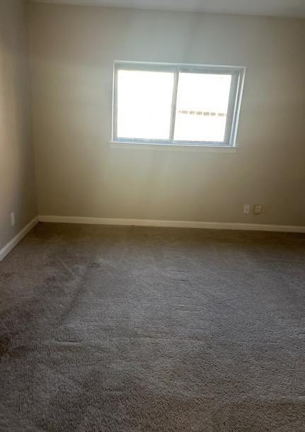 empty room with dark colored carpet and a healthy amount of sunlight