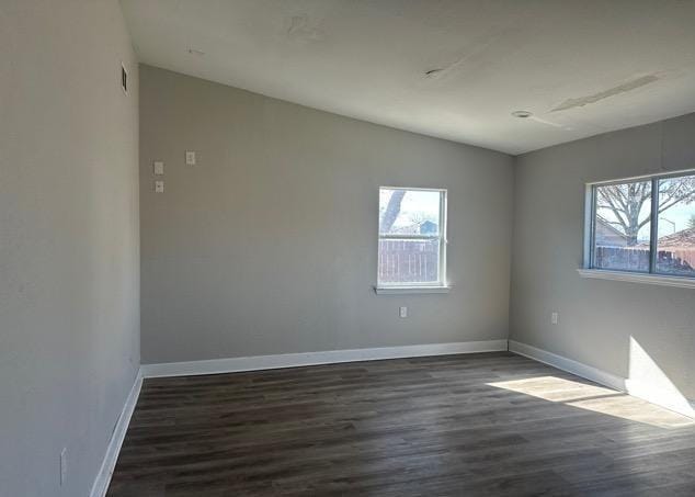 empty room featuring dark hardwood / wood-style flooring and a wealth of natural light