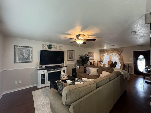 living room with dark wood-type flooring, ceiling fan, and a textured ceiling