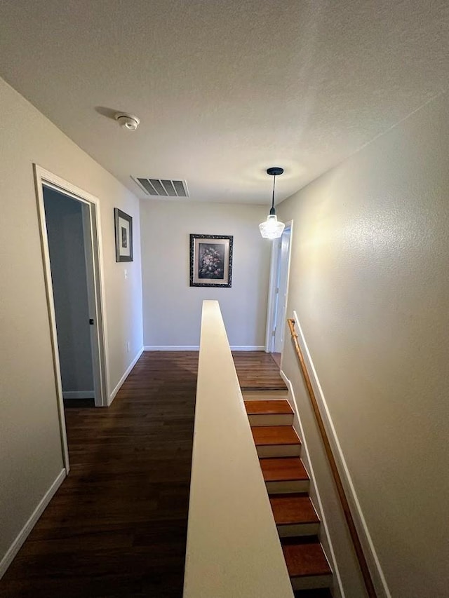 corridor with dark wood-type flooring and a textured ceiling