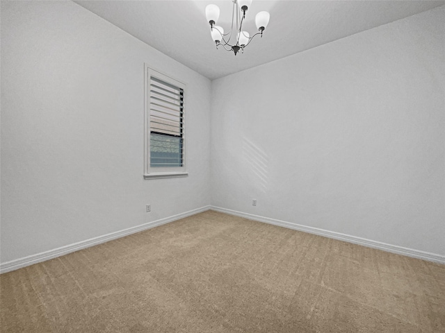 spare room with carpet and a chandelier