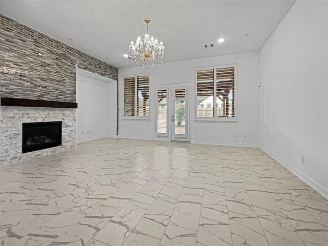 unfurnished living room featuring french doors, a large fireplace, and a notable chandelier