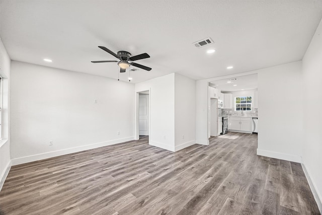 unfurnished living room featuring a ceiling fan, visible vents, light wood-style flooring, and baseboards