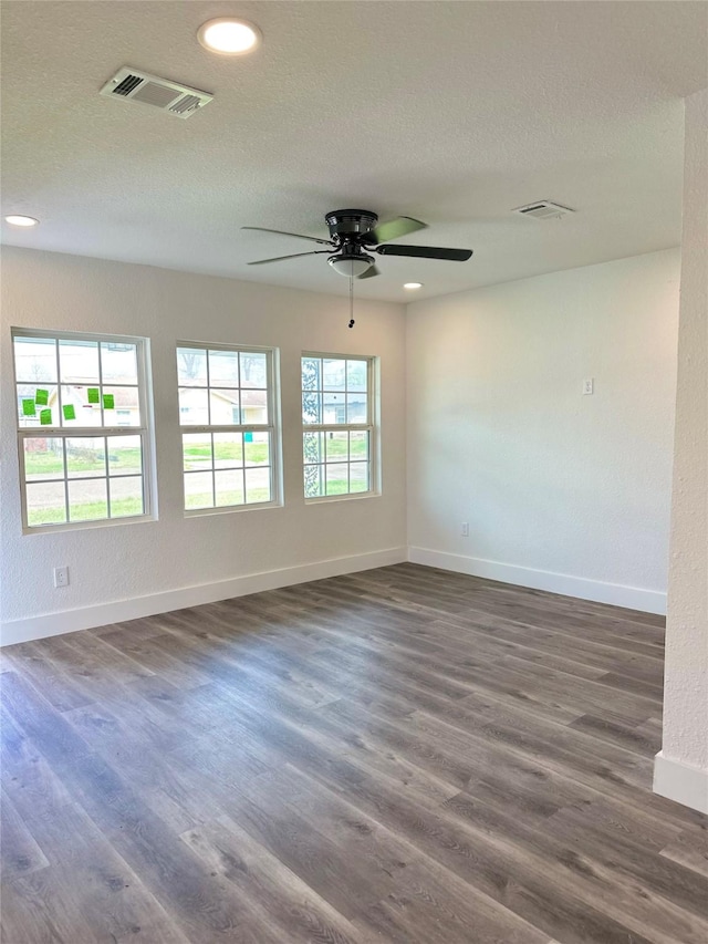 spare room featuring dark wood-style flooring, visible vents, plenty of natural light, and baseboards