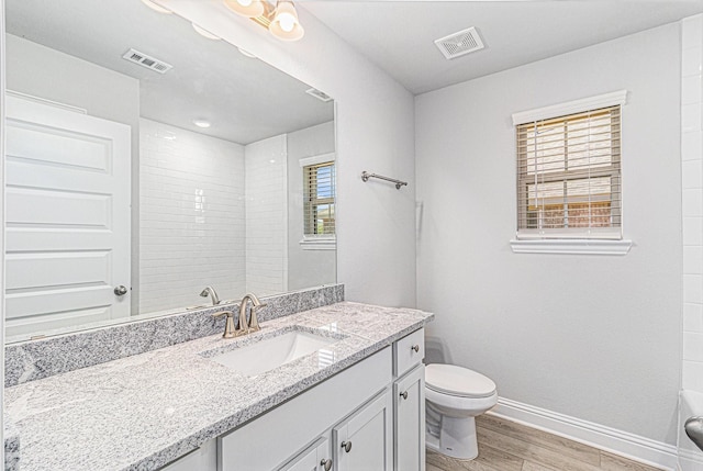 full bath with toilet, wood finished floors, vanity, visible vents, and baseboards