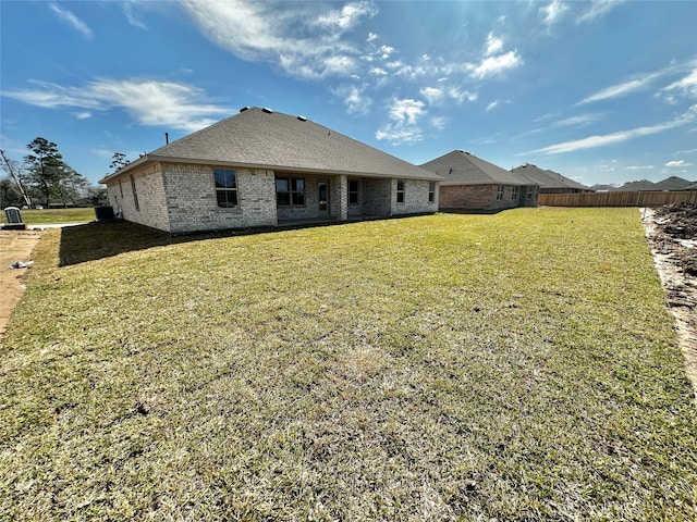 back of property with fence, a lawn, and brick siding