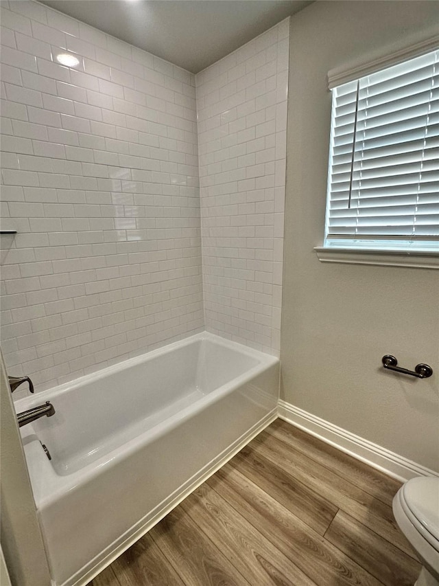 bathroom with shower / washtub combination, baseboards, toilet, and wood finished floors