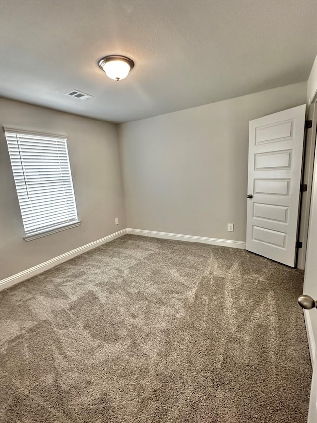 carpeted spare room featuring visible vents and baseboards